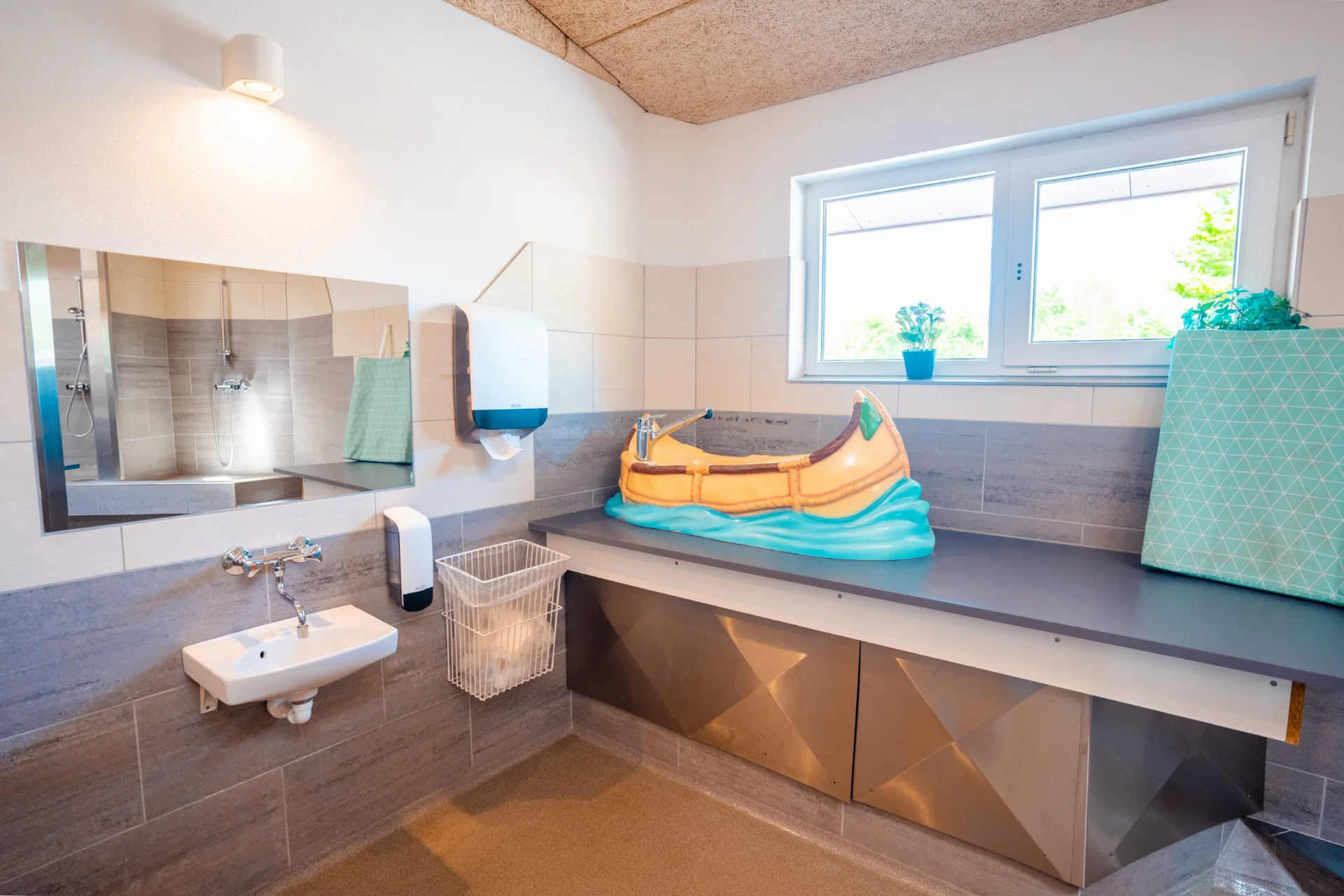 Baby changing room with a fun canoe-shaped washbasin for children